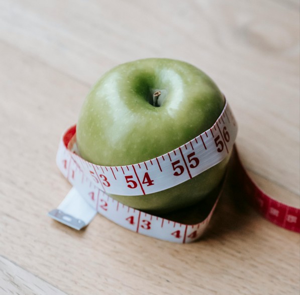 Apple wrapped with measuring tape representing nutrition consulting and healthy food choices