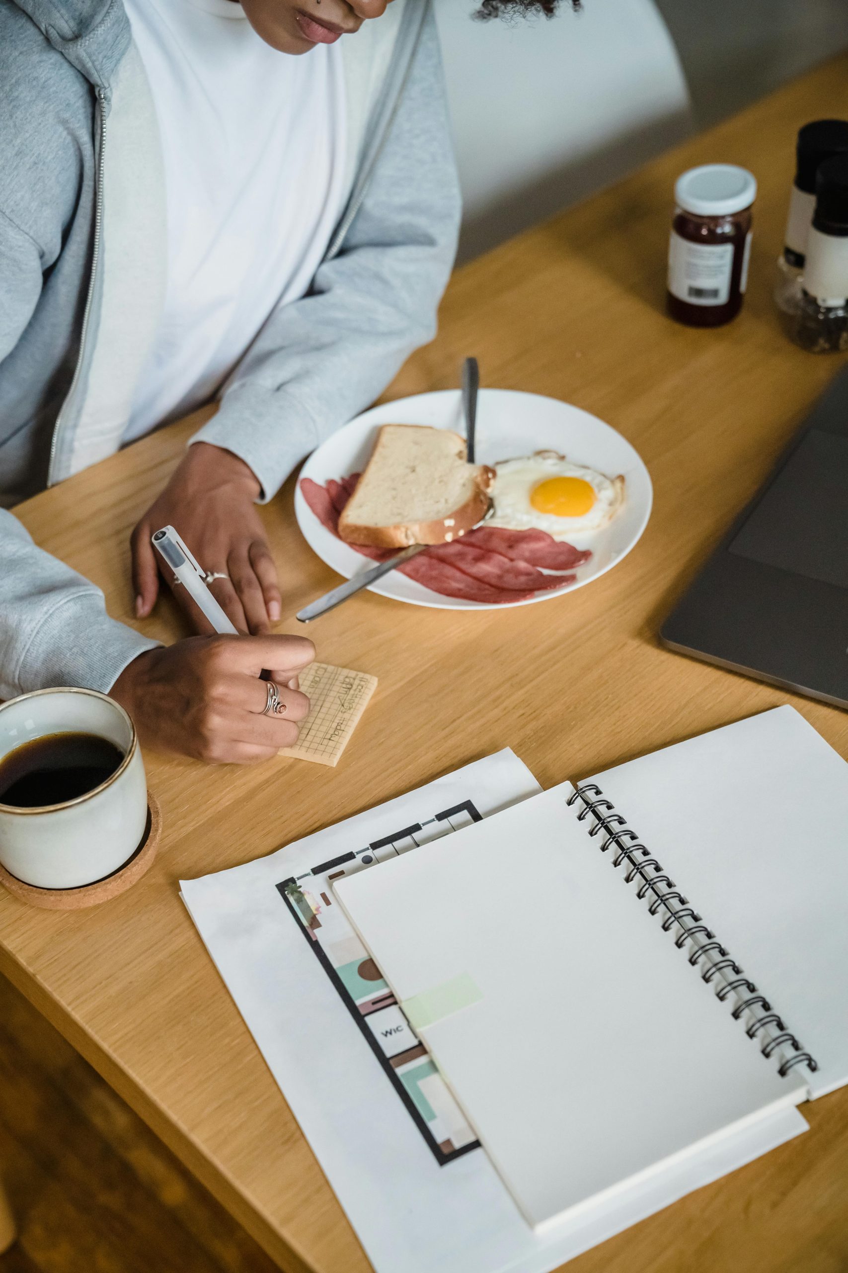 Person planning a meal beside breakfast and a notebook for nutrition consulting support