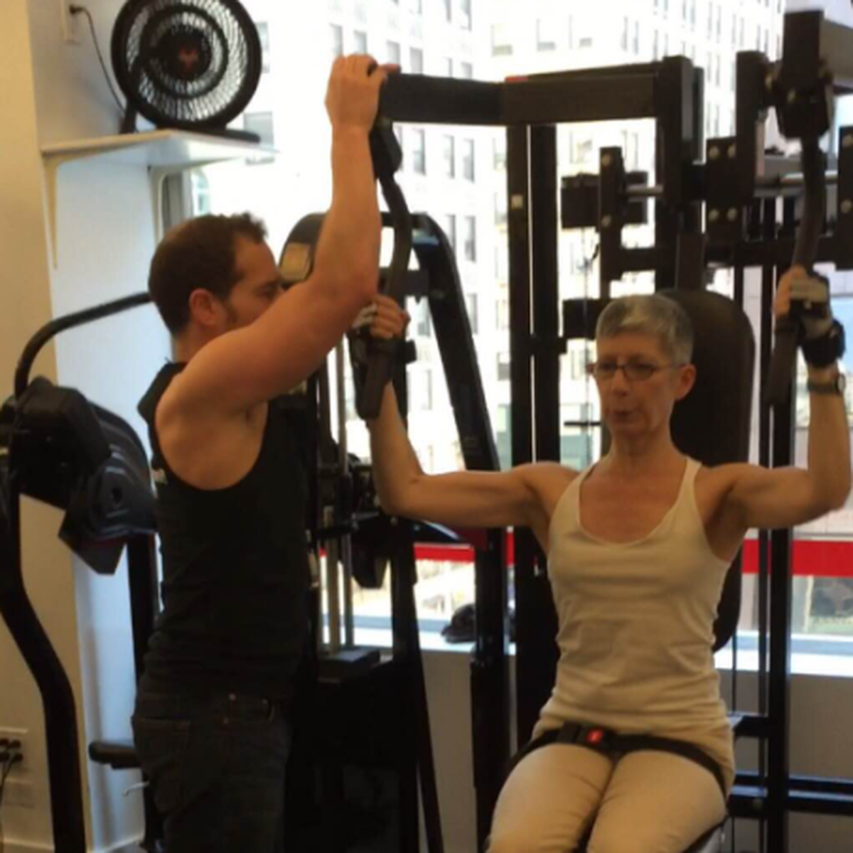 Personal trainer guiding a client through controlled strength training on specialized equipment at Pure Conditioning